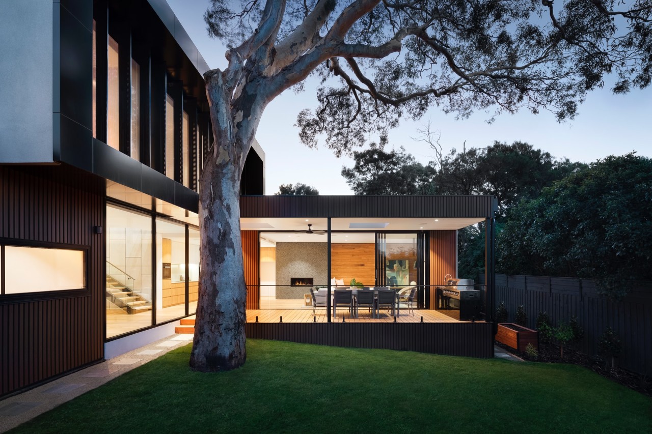 Exterior view of a well-lit home from the backyard as the sun sets