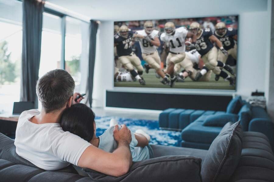 A couple watches a football game in their luxury home theater.