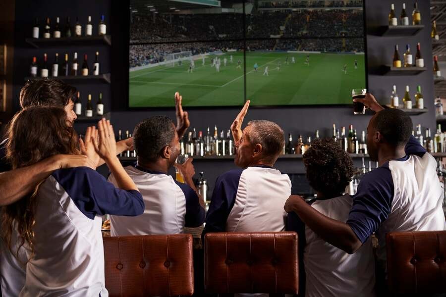 A group of people watch a soccer game in a bar’s video wall.