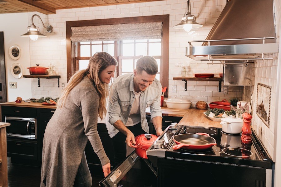 Man and woman working together to put a pot into the oven of a luxury kitchen